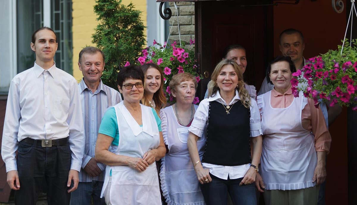 Hotel staff gathered in the doorway under hanging baskets of flowers