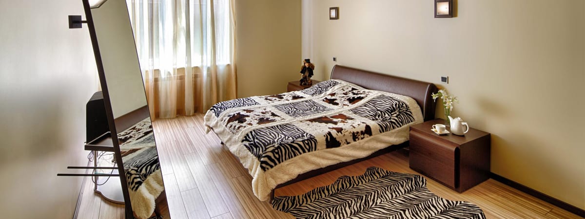 Zebra-print bedspread and rug with a mirror above the low chest