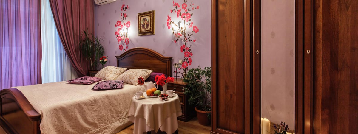 Cherry-blossom wallpaper behind a bed dressed in white