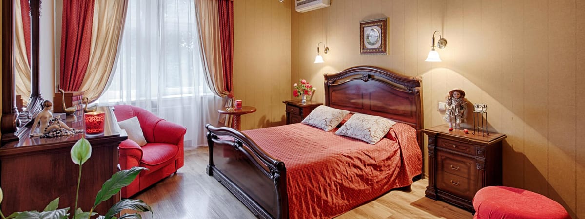 Ochre bedroom with a red bedspread and a carved sleigh bed