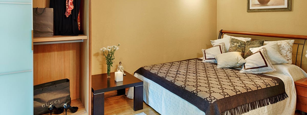 Ochre bedroom with an open wardrobe standing beside the bed